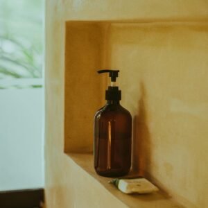 A minimalist bathroom shelf showcasing an amber soap dispenser and bar soap, exuding elegance.