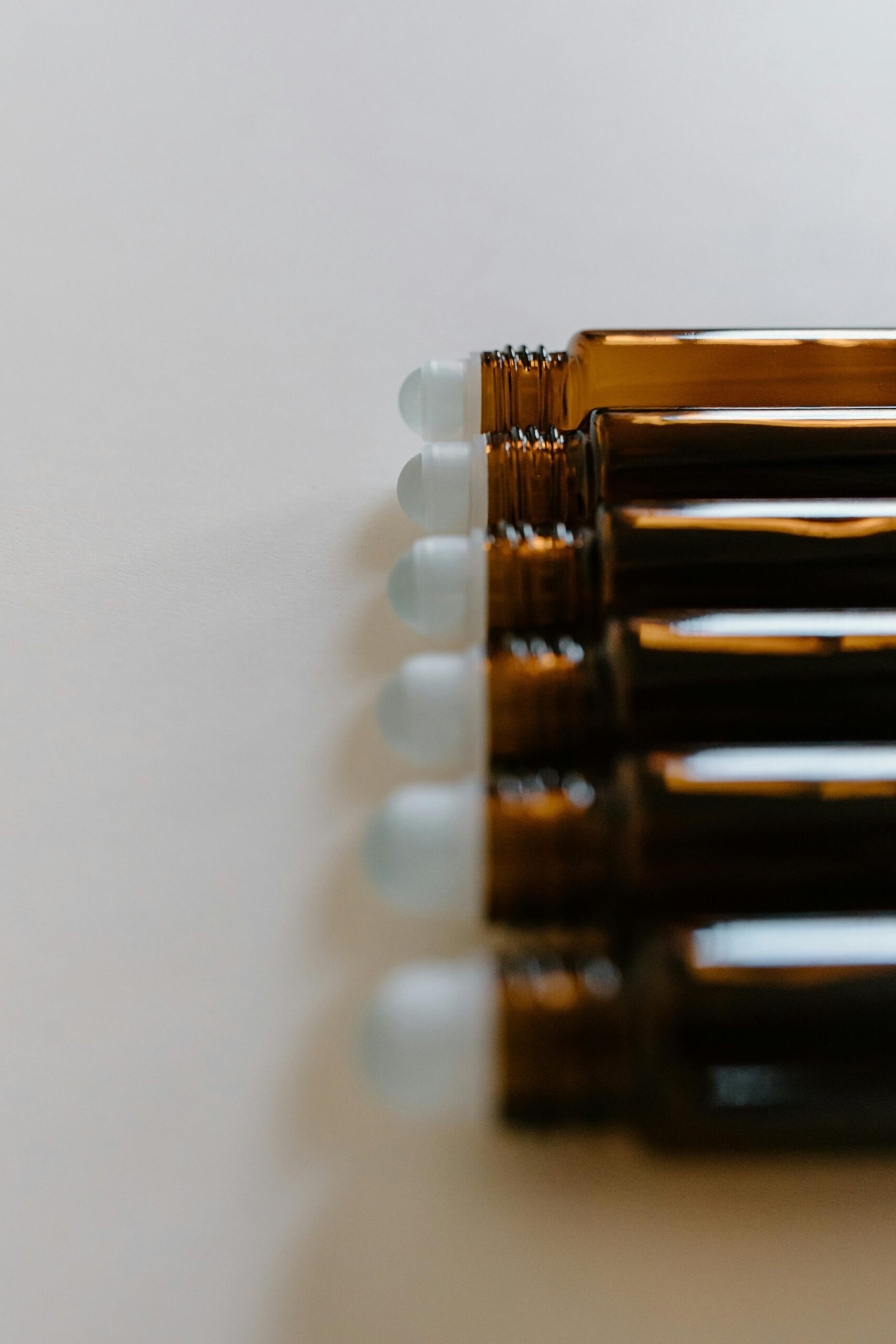 pexels photo 6693902 6693902 A line of amber glass roll-on bottles on a soft white background, perfect for essential oils.