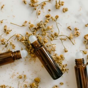 Brown roll-on bottles with dried chamomile flowers on a white background.