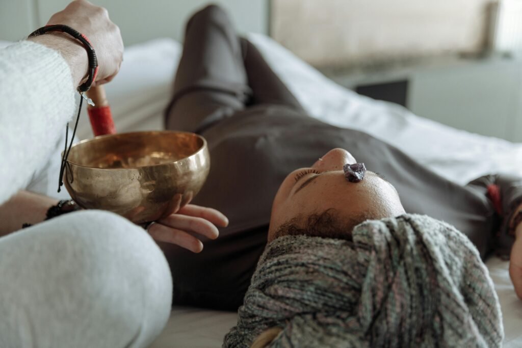 Explore Healing Sessions A serene relaxation therapy session with a Tibetan singing bowl and crystal on forehead, promoting spiritual healing.
